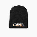 Black knit beanie with "CONNIE" embroidered in white and orange letters on front.